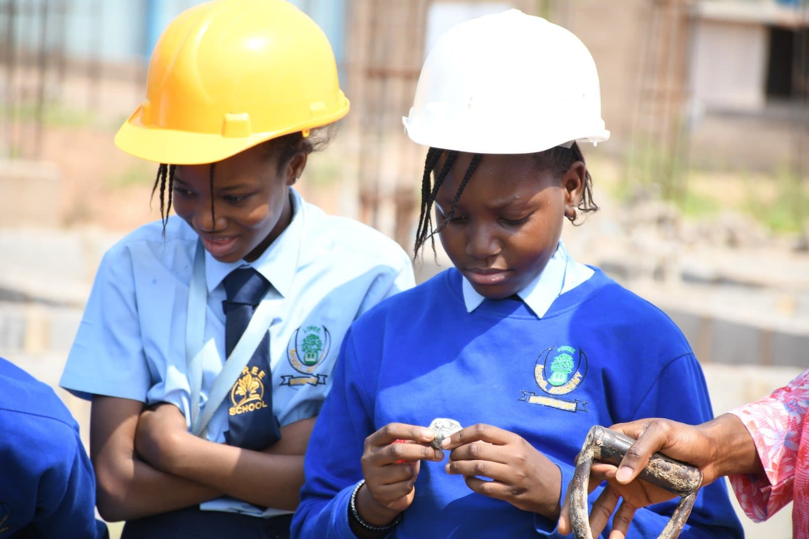 Two students wearing safety helmets and practising a hands-on activity